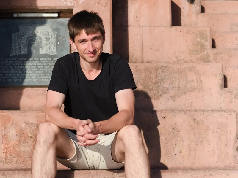 Kristjan Vingel sitting on a staircase and looking into a camera